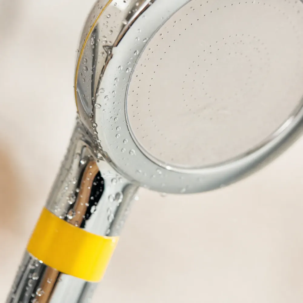 Close up of the shower head face plate and yellow band with water droplets